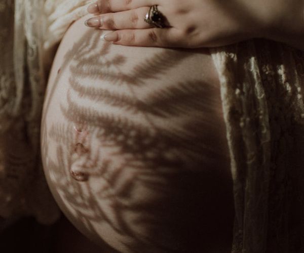 Close-up of a pregnant woman's hands on her belly, breathing deeply.